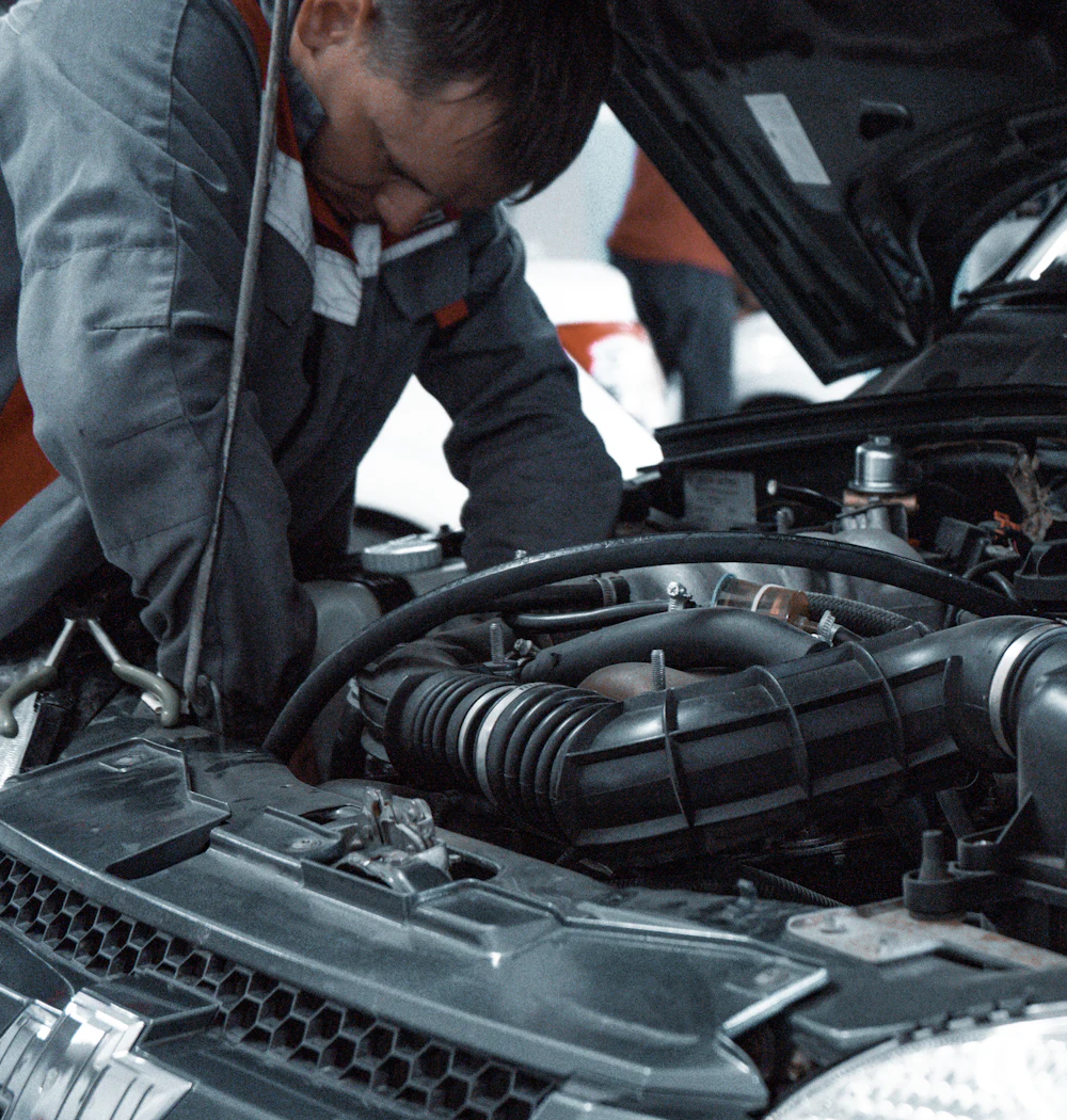 A mechanic in a gray uniform inspecting an engine